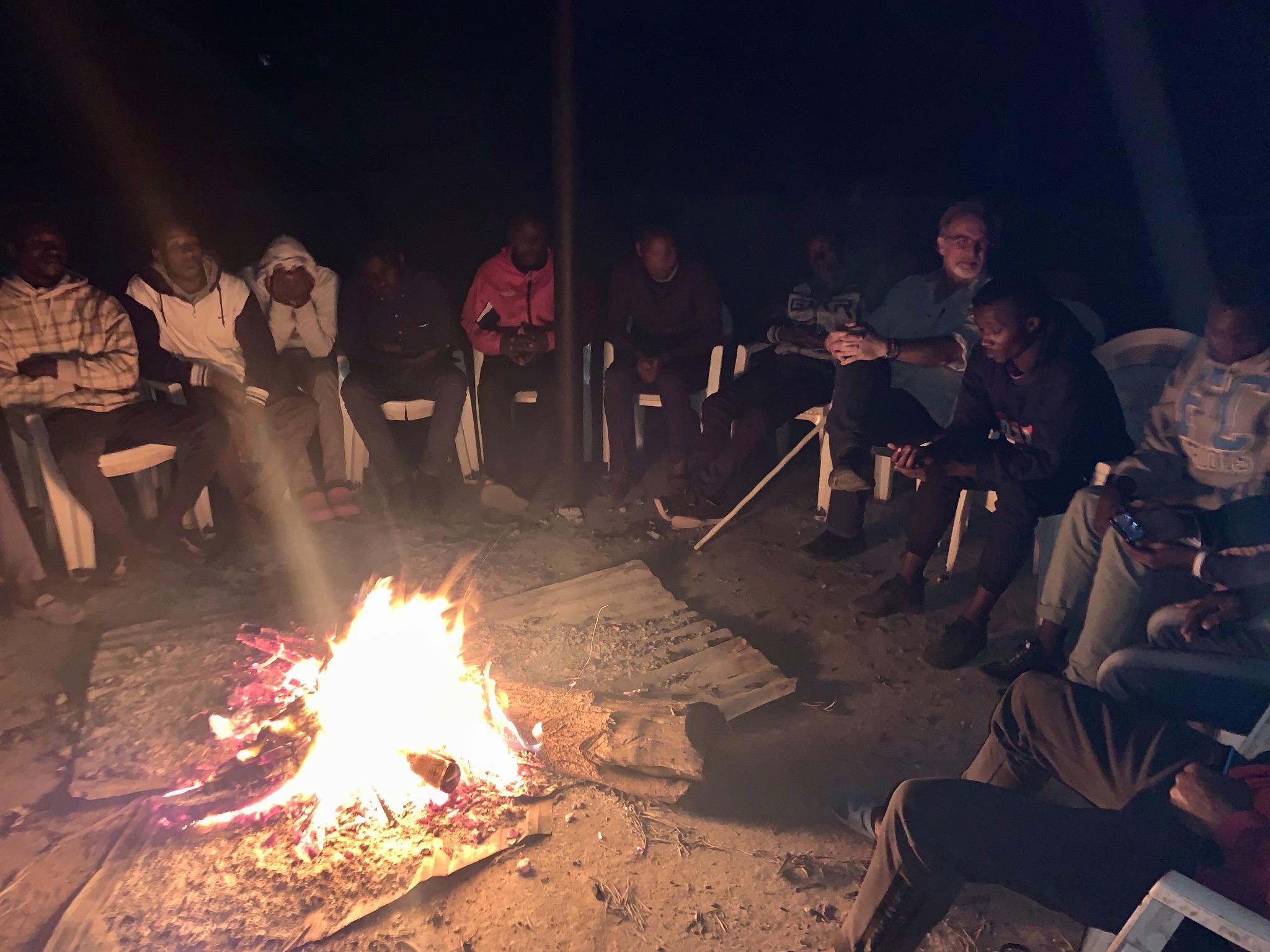 Clay Boykin and Kenyan men gathered around a fire at night in a circle