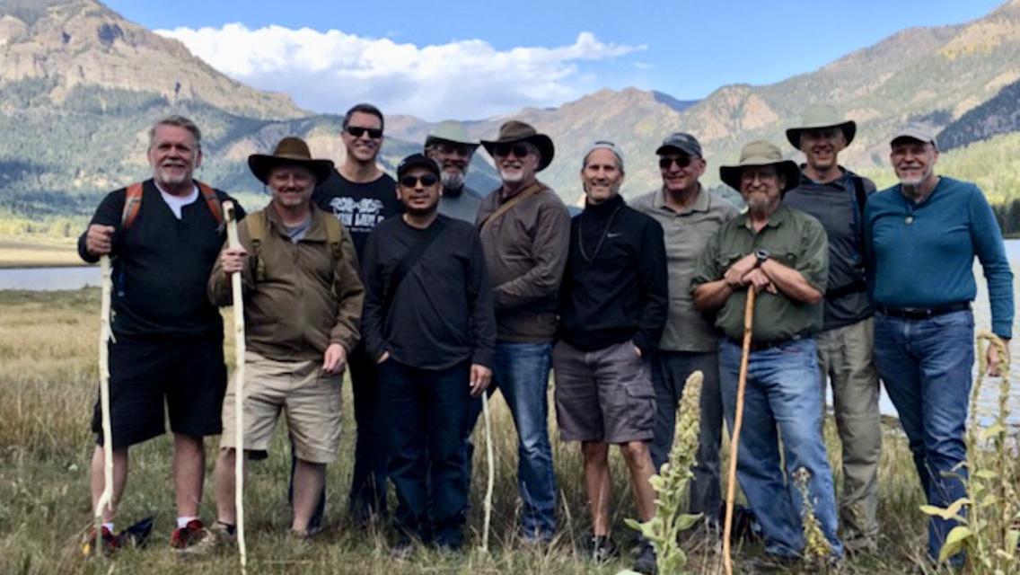 Men standing together in a mountain valley during a retreat